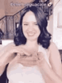 a woman is making a heart shape with her hands while smiling .