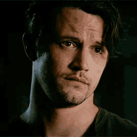 a man with a beard is looking at the camera with a sad look on his face