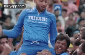 a man in a blue shirt is being carried by a group of people .