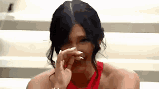 a woman in a red dress is laughing and covering her mouth with her hand
