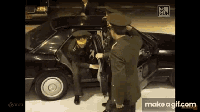 a man in a military uniform is getting out of a black car
