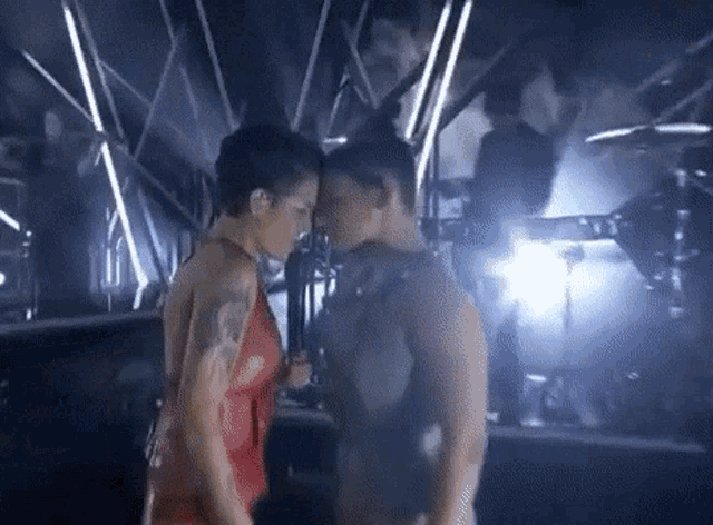 a man and a woman are kissing on a stage while holding microphones .