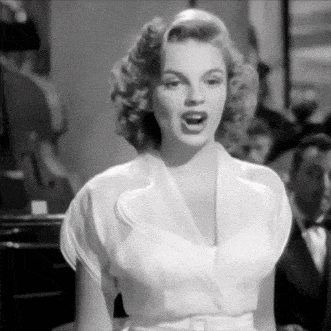 a woman in a white dress is singing in front of an orchestra