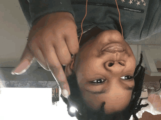 a person wearing ear buds and a grey sweatshirt with stars on it