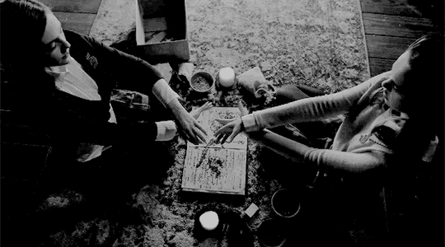 a black and white photo of two women sitting on the floor .