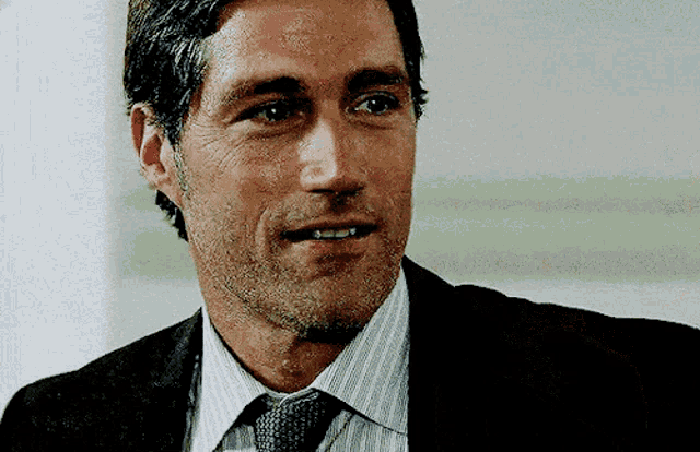 a man wearing a suit and tie is smiling