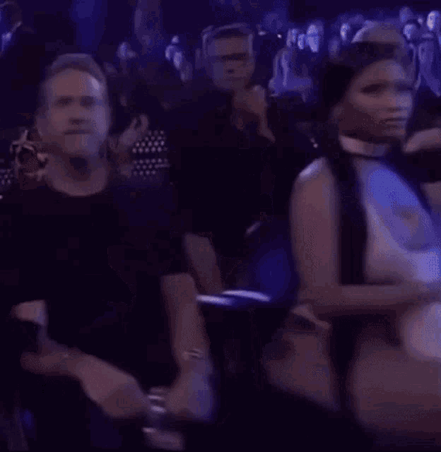 a woman in a white dress is sitting in a crowd of people at a concert .