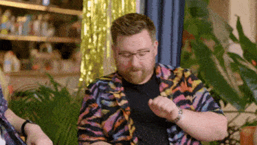 a man with a beard wearing glasses and a colorful shirt
