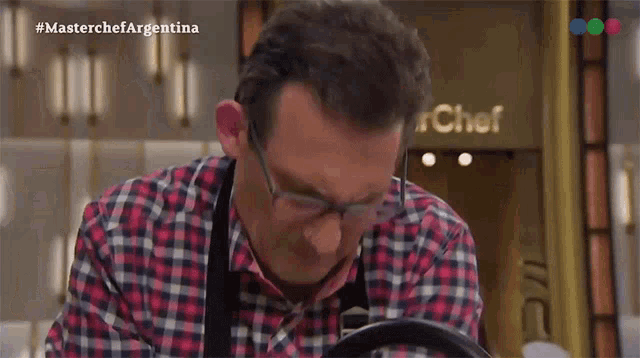 a man in a plaid shirt is standing in front of a chef sign