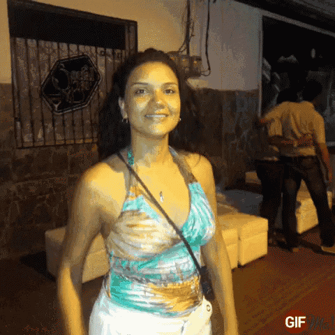 a woman in a blue top is smiling in front of a sign that says " gif "
