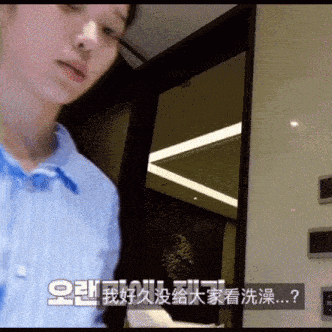 a woman in a blue shirt stands in a room with chinese writing on the wall