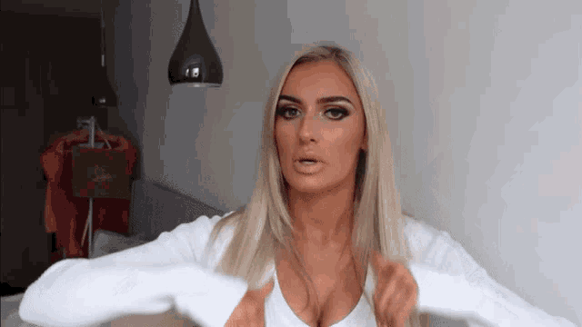 a blonde woman wearing a white sweater with a huge cleavage