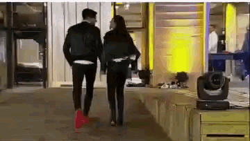 a man and a woman walking down a sidewalk holding hands .