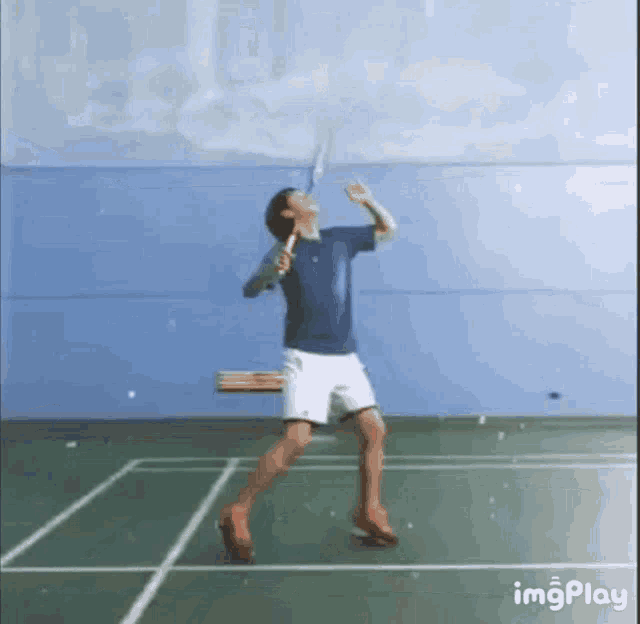 a man is playing badminton on a court and swinging a tennis racket .