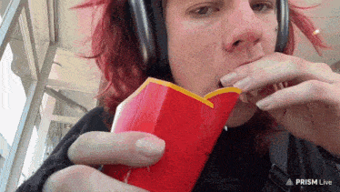 a person wearing headphones eating french fries from a red box