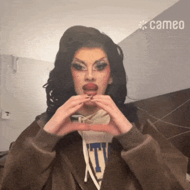 a woman making a heart shape with her hands and a cameo logo in the background