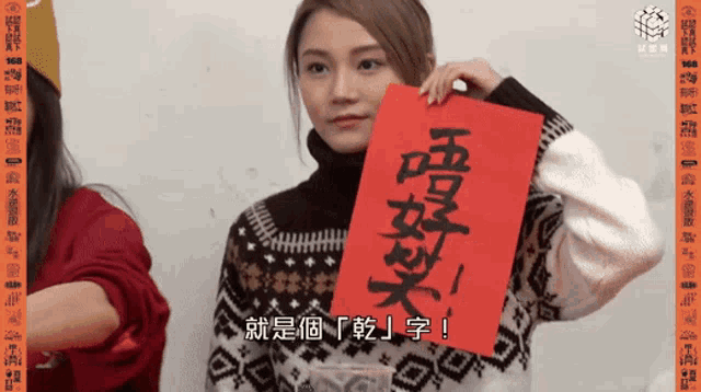 a woman in a sweater holds a piece of paper with chinese writing on it