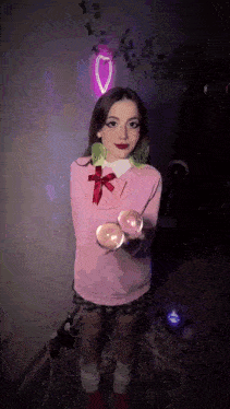 a girl in a pink sweater and plaid skirt is holding two balloons
