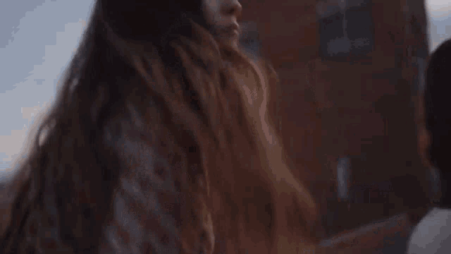 a woman with long hair is standing in front of a building and looking at the camera .