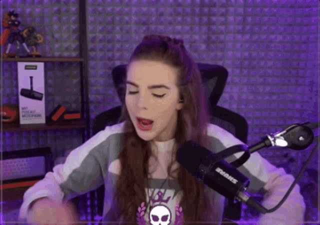 a girl is sitting in front of a shure microphone .