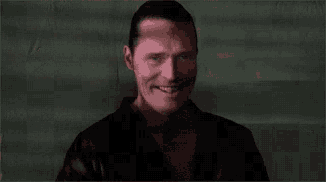 a man with a red face is smiling in front of a green background