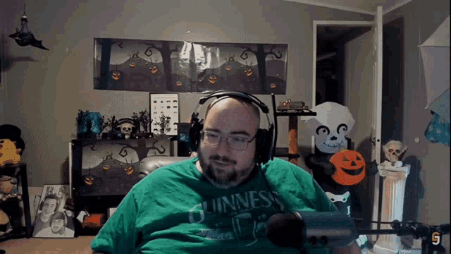 a man wearing a green shirt that says guinness sitting in front of a microphone