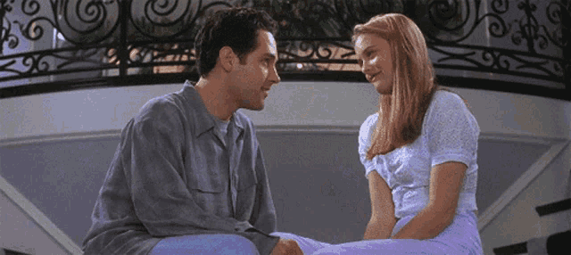 a man and a woman look at each other on a balcony