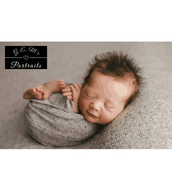 a newborn baby wrapped in a grey blanket is smiling for the camera