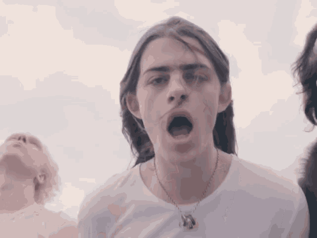 a young man with long hair is wearing a necklace with a horse on it