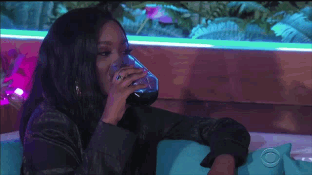 a woman is sitting on a couch drinking a glass of water