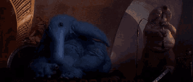 a blue monster is standing next to a man holding a gun