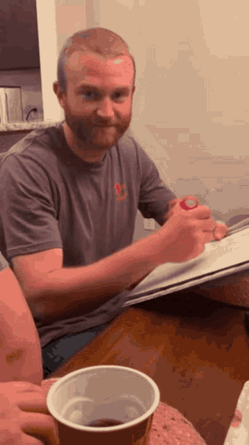 a man with a beard is sitting at a table with a cup of tea