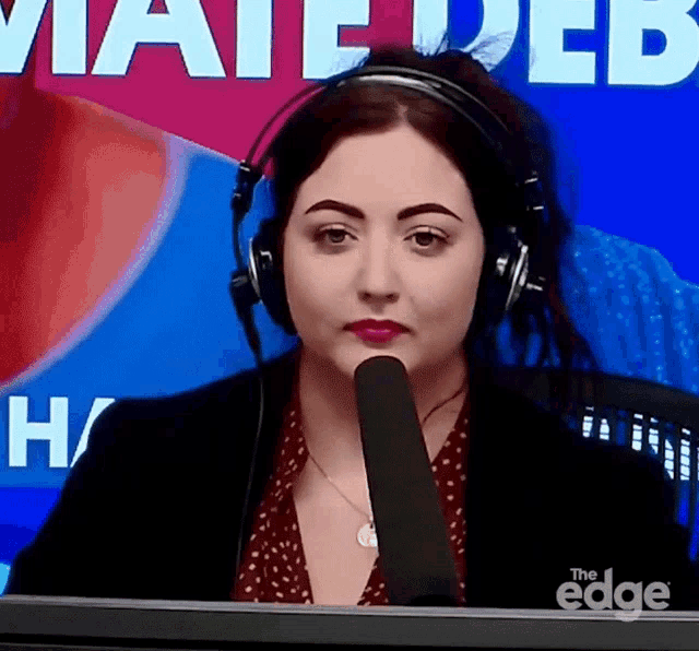 a woman wearing headphones stands in front of a sign that says " mate web "