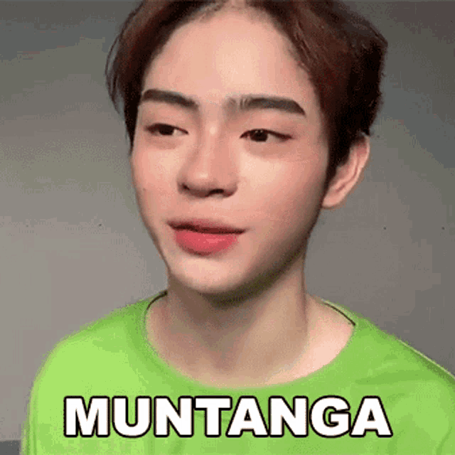 a young man in a green shirt is making a funny face and the word muntanga is on his shirt .