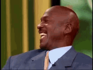 a man in a suit and tie is laughing and smiling