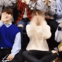 a group of people are sitting on the floor with their legs crossed and covering their faces .