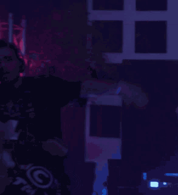 a man wearing headphones and a shirt that has the letter g on it is dancing in a dark room