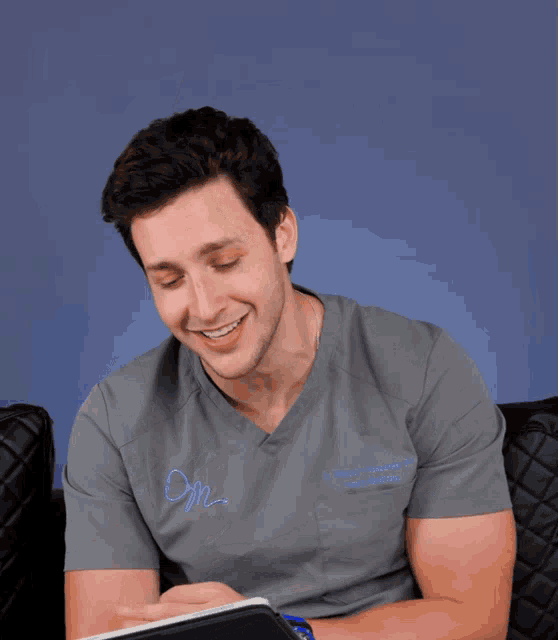a man wearing a grey scrub top with the letters o.f.m. on it
