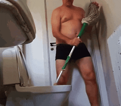 a shirtless man in black underwear is holding a mop over a toilet