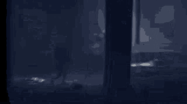 a person is standing in a dark room with a light shining through the ceiling .