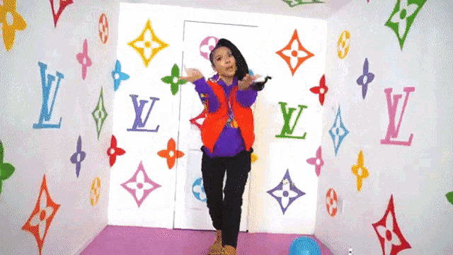 a woman dancing in a room with louis vuitton logos on the walls