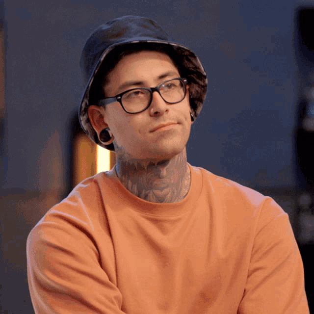 a man with a tattoo on his neck wears a hat and glasses