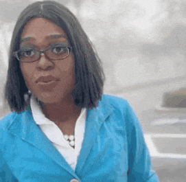 a woman wearing glasses and a blue jacket is standing on a street .