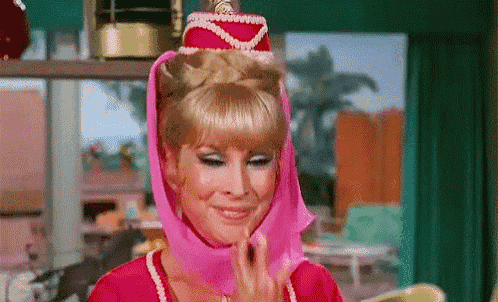 a woman in a pink dress and pink hat is smiling in a room .