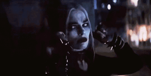harley quinn from suicide squad is giving the middle finger while looking at the camera .