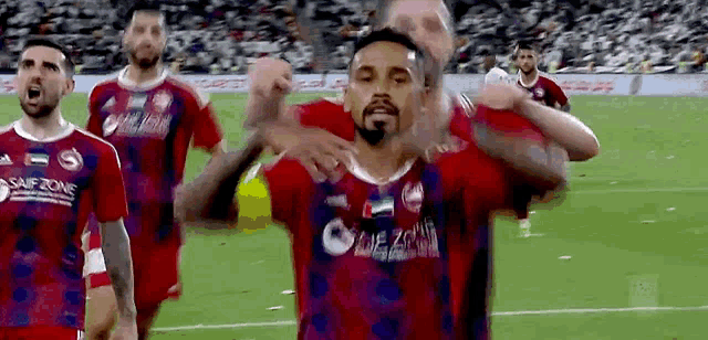 a group of soccer players are on a field with one wearing a shirt that says saifzone