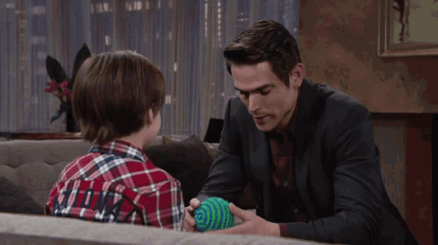 a man in a suit sits next to a boy in a plaid shirt with the word love on his back