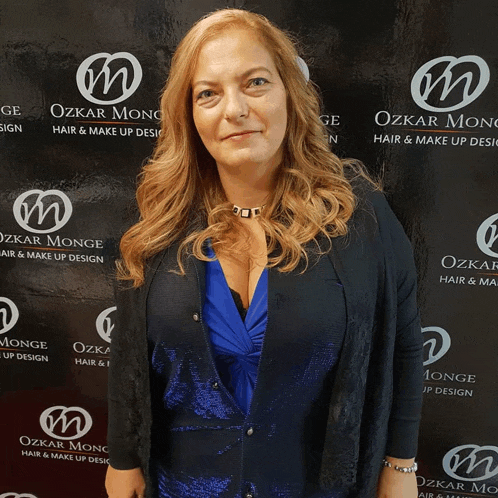 a woman stands in front of a wall that says ozkar monge hair & make up design