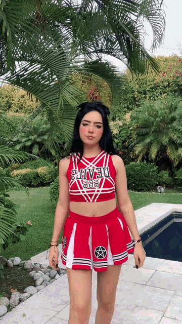 a girl in a cheerleader outfit is standing in front of a pool