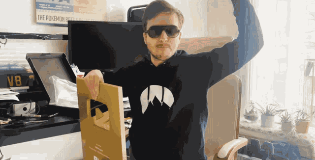 a man wearing sunglasses is holding a gold plaque in front of a poster that says the pokemon battle of the century